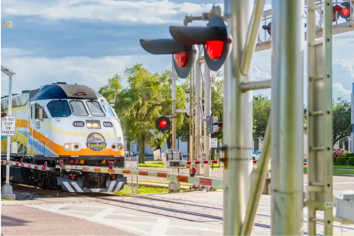 SunRail train passes by a crossing grade while the crossbucks flash and the gate is down.