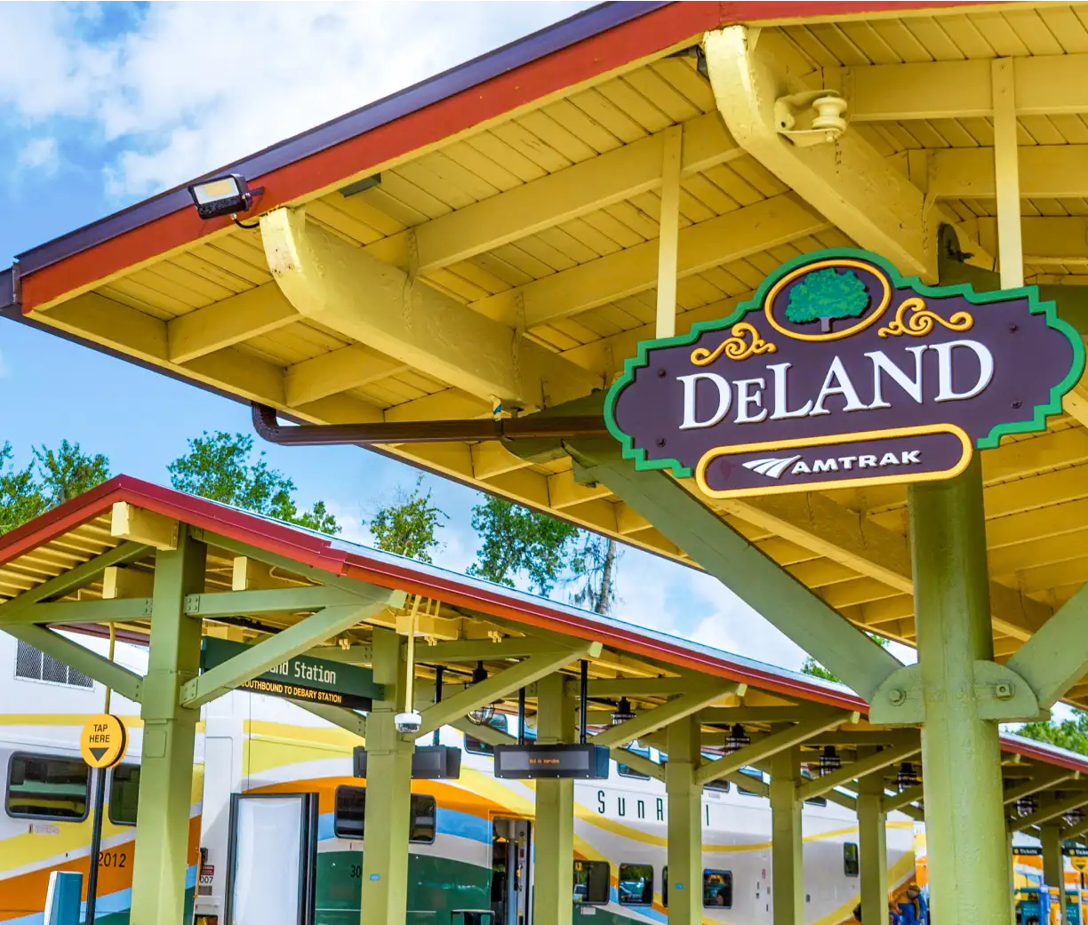 DeLand/Amtrak signage at the SunRail Station with SunRail train in the background.